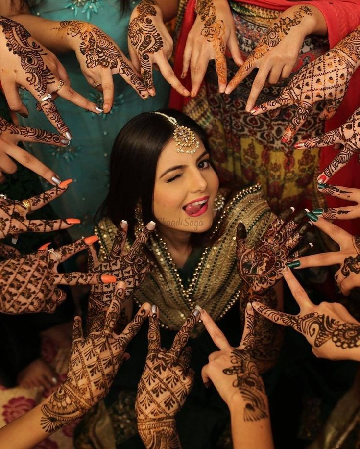 Friends displaying their mehendi designs around the bride