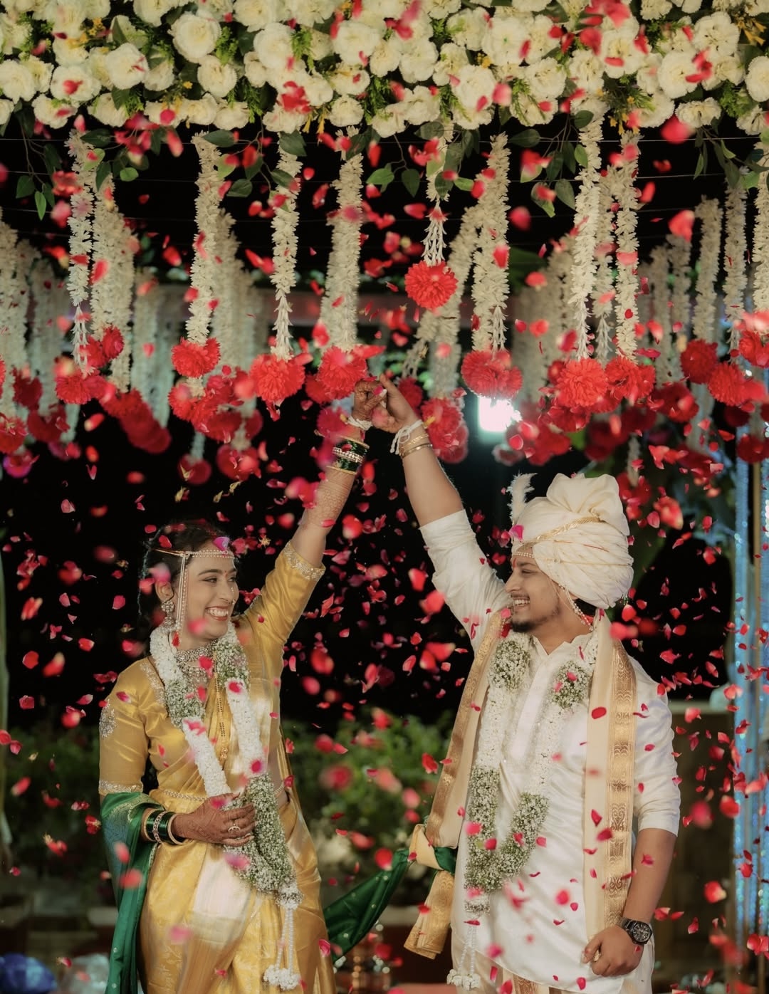 Newly married couple celebrating under falling flower petals
